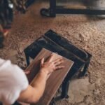 person touching brown plank