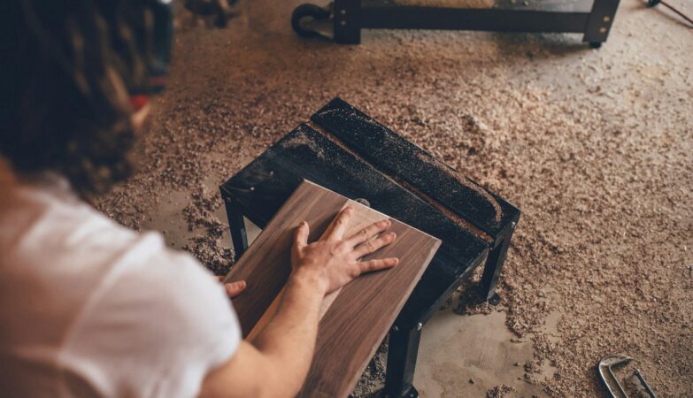 person touching brown plank