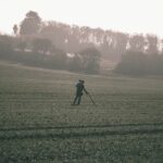 man in black jacket walking on green grass field during daytime