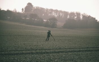 man in black jacket walking on green grass field during daytime